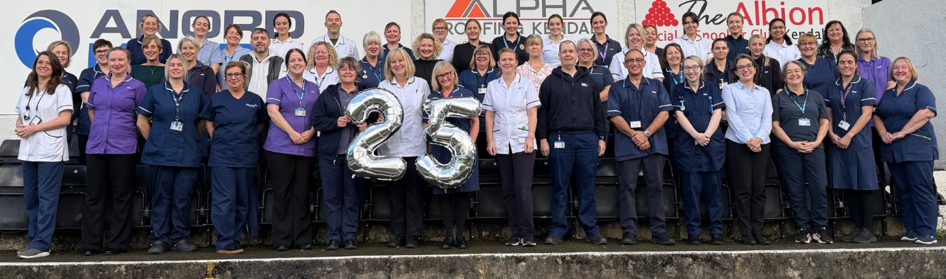 Group photo of the community respiratory team holding large silver 25 balloons to signify their anniversary