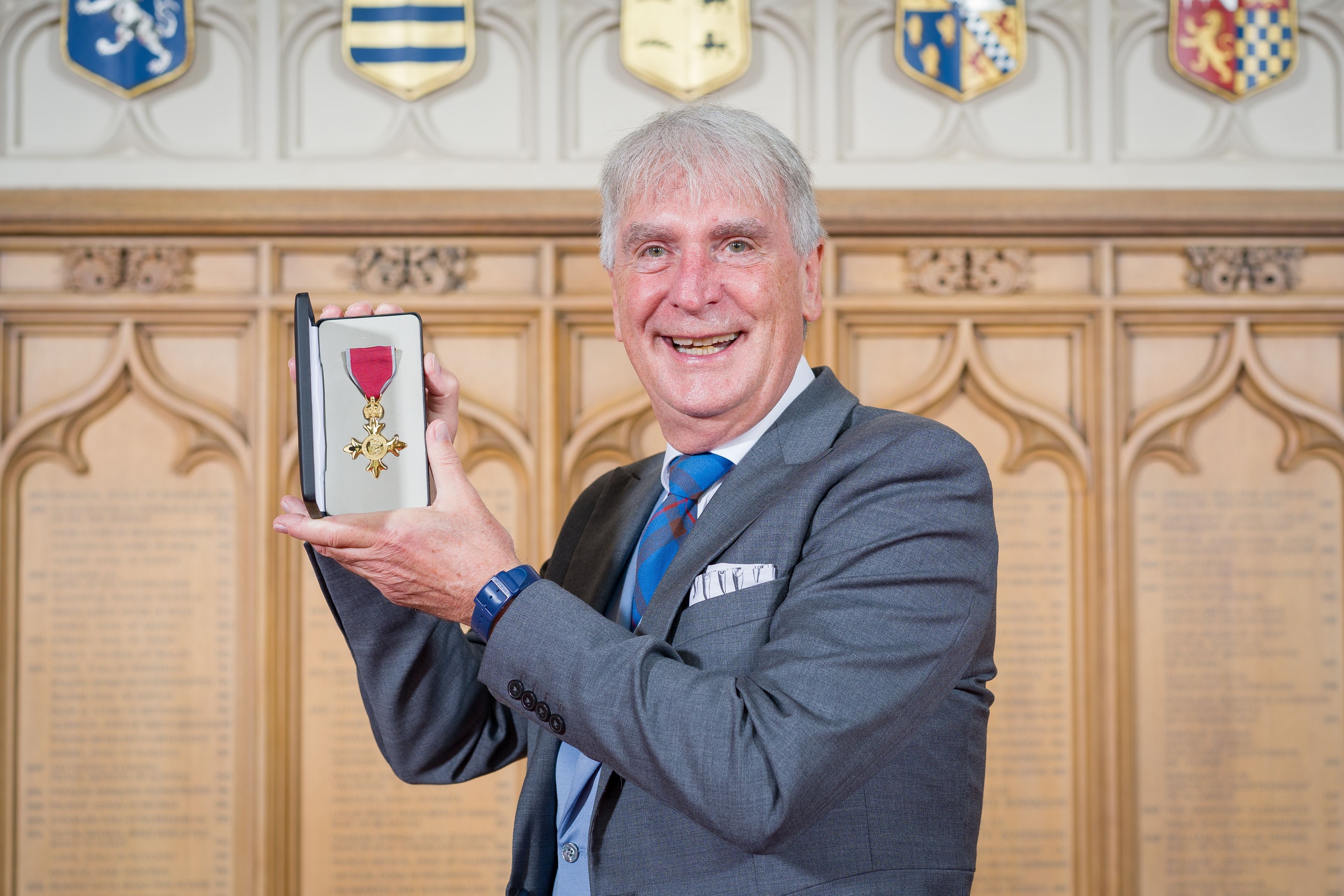 Peter Dyer holding his OBE medal