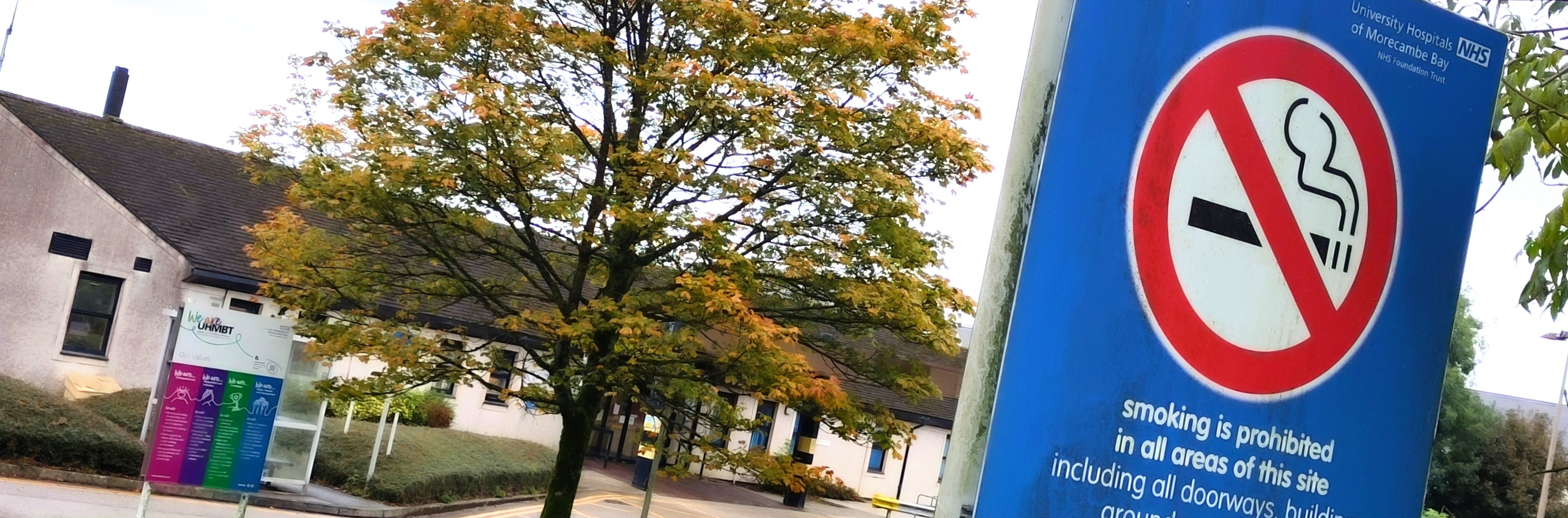 A large blue sign with a cigarette under a red cross outside Westmorland General Hospital